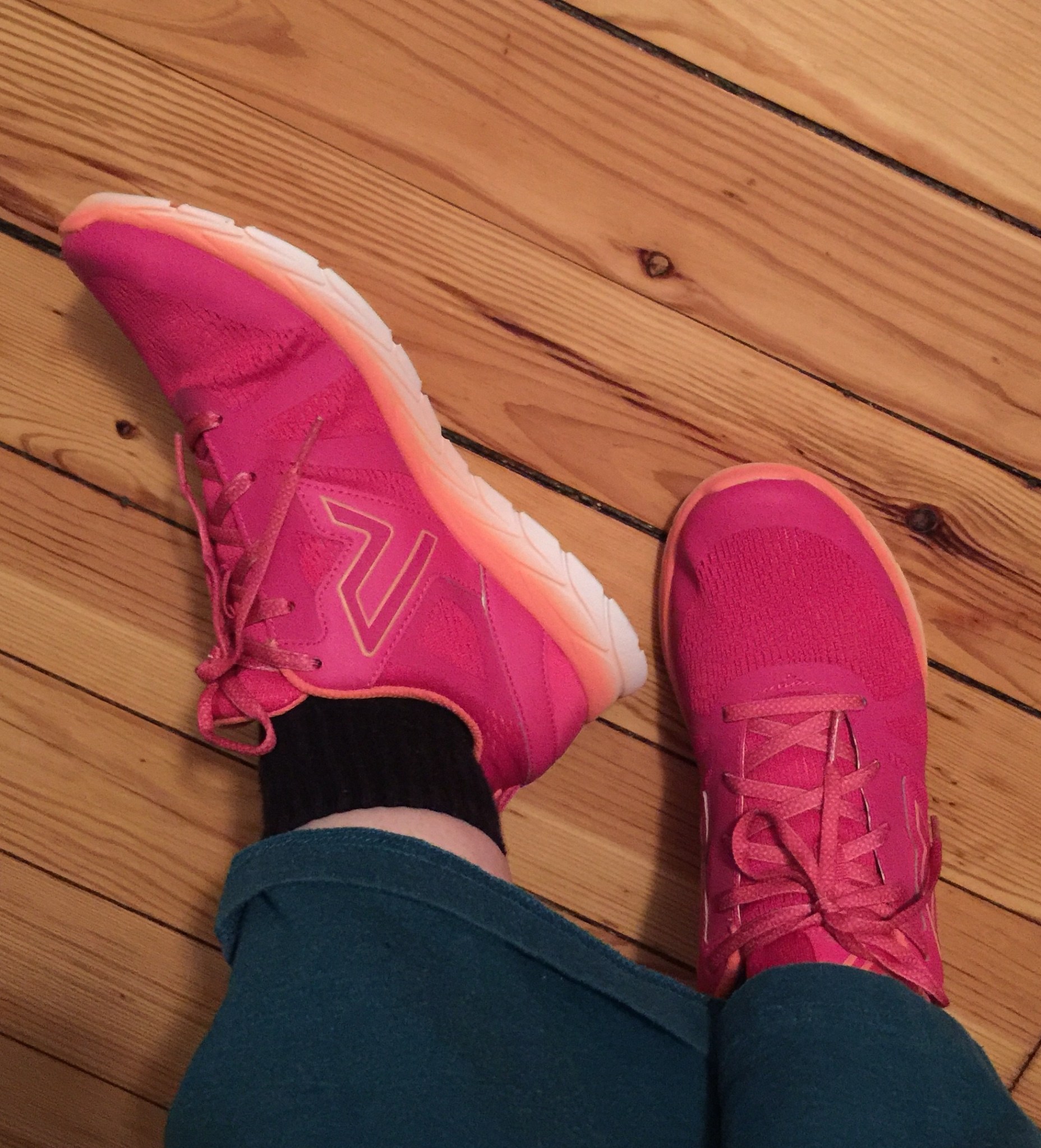 Bright pink sneakers with orange along the bottom edge and top of cuffs.